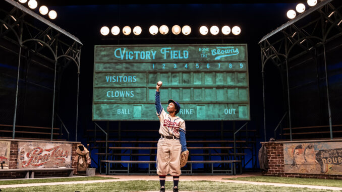 Toni holds a baseball up in the air triumphantly